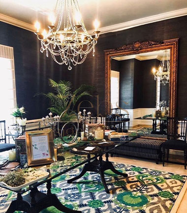 A stylish living room featuring a chandelier, elegant furniture, and a decorative rug on the floor.